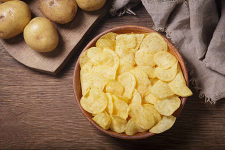 bowl of potato chips on wooden table, top viewの写真素材