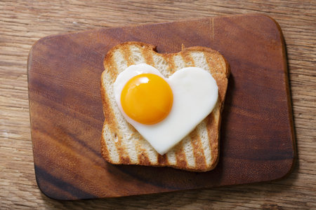 Breakfast with shapped heart fried egg and toasted bread, top view. Valentines day food