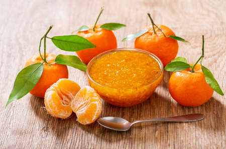 bowl of tangerine or tangerine jam with fresh fruits on wooden tableの写真素材