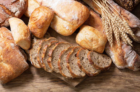 Fresh baked bread and wheat ears on a wooden background, top viewの写真素材