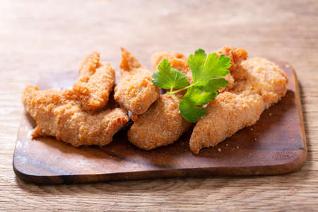 fried chicken with parsley on a wooden boardの写真素材