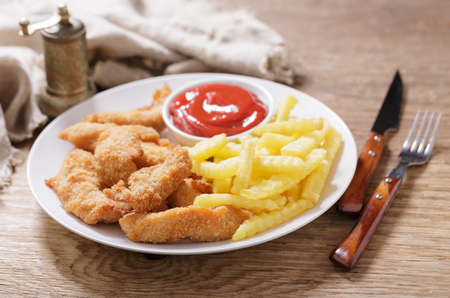 plate of fried chicken with french fries on wooden tableの写真素材