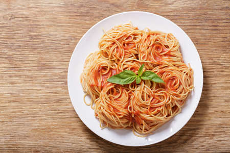 plate of pasta with tomato sauce on wooden background, top viewの写真素材