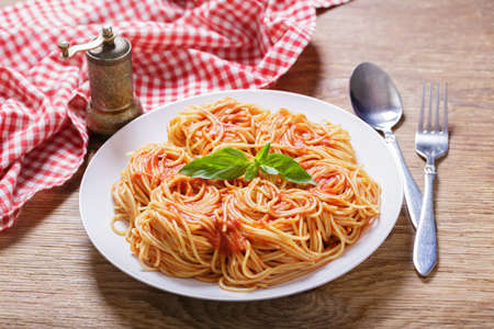 plate of pasta with tomato sauce on wooden tableの写真素材