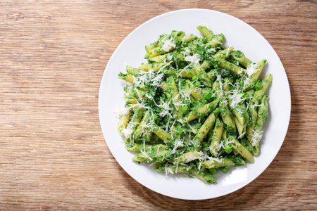 plate of pasta with spinach, peas and parmesan cheese on wooden background, top viewの写真素材