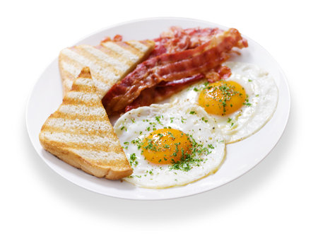 plate of fried eggs, bacon and toast isolated on white backgroundの写真素材