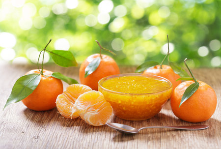 bowl of tangerine or tangerine jam with fresh fruits on wooden tableの写真素材
