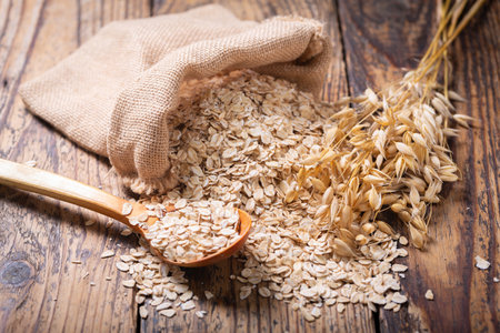 oatmeal flakes and ears of oat on wooden tableの写真素材