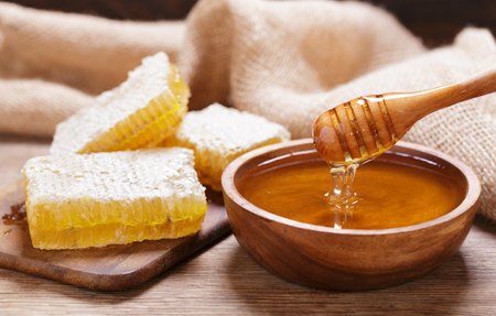 Bowl of honey and honeycomb on wooden tableの写真素材
