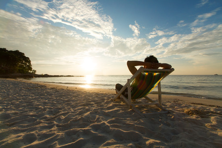 Man relax on chair beach in vacations with sunset and blue sky background.