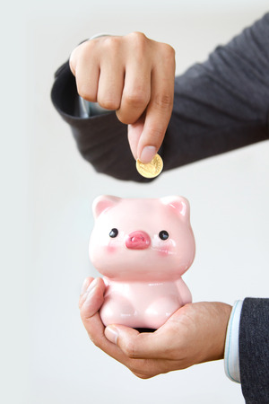 Businessmen putting money coin in piggybankの写真素材