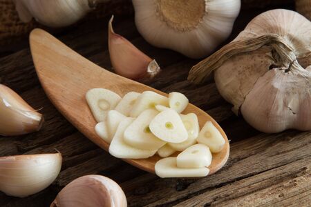 Close up peel garlic sliced on wooden spoonの写真素材