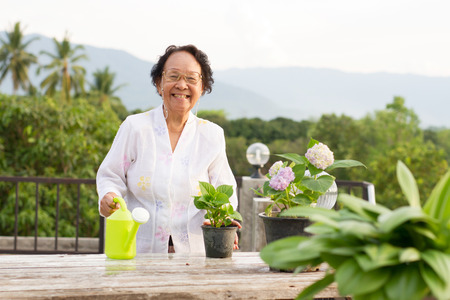 Cheerful elderly woman looking at camera and smiling while doing her hobby, happy retirement concept.の写真素材