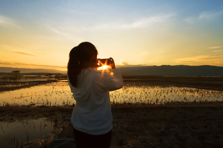 Landscape nature scene of women shooting the photo at dramatic sky of beautiful sunset.の写真素材