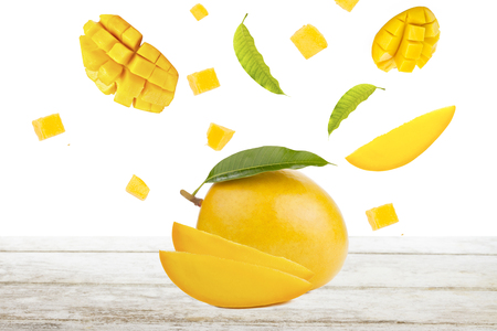 Mango and falling of cut slice with leaf on white wood, isolated backgroundの写真素材