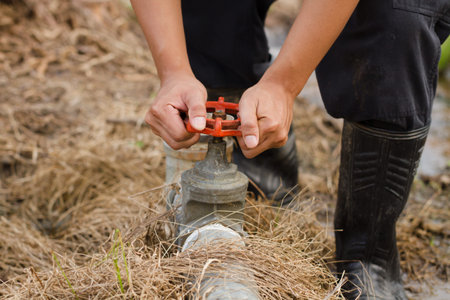 Farmer open irrigation water valve to watering his crop plant at farm fields.