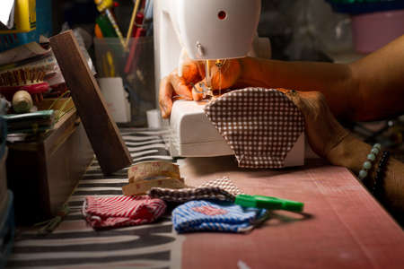 Old woman making a surgical mask by using a sewing maching for her family to prevention of corona virus or air pollution.の写真素材