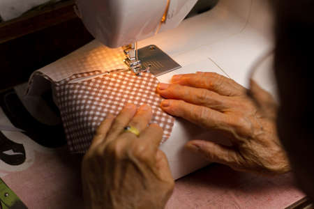 Old woman making a surgical mask by using a sewing maching for her family to prevention of corona virus or air pollution.の写真素材