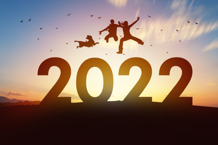 Dog with owner family jumping over 2022 at beautiful sunset.