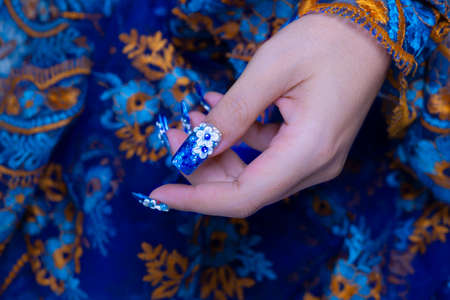 beautiful shiny dark blue glitter gel nail art ombre design painting 3D white cute flower decorated with rhinestone on woman long square shape fingernailの写真素材