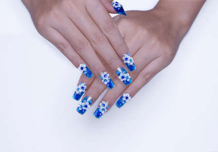 beautiful shiny dark blue glitter gel nail art ombre design painting 3D white cute flower decorated with rhinestone on woman long square shape fingernail isolated on white backgroundの写真素材