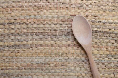 Wooden spoon placed on traditional wickerwork texture made form dried stalk water hyacinth or Eichhornia crassipes. Top view with copy space.の写真素材