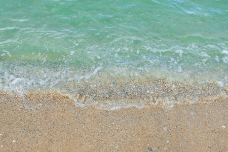 Soft wave of emerald ocean on sandy beach for background.