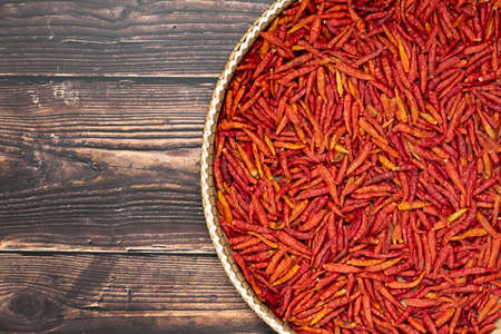 Dried chilies the threshing basket on wooden table with copy space. Top view, flat lay of ingredient for cooking.の写真素材
