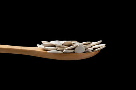 Close up pumpkin seeds in wooden spoon on black background.の写真素材
