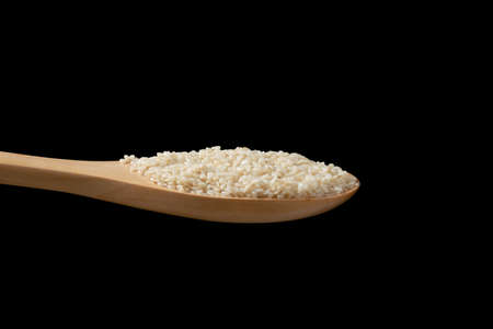 Close up white sesame seeds in wooden spoon on black background.の写真素材