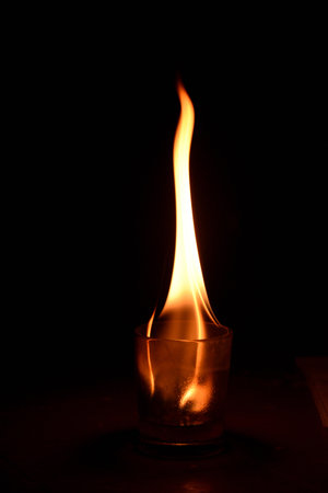 Burning candle in a glass on a black background, close-upの写真素材