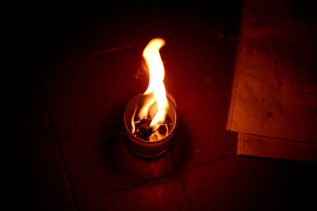 Burning candle in a candlestick on a dark background.