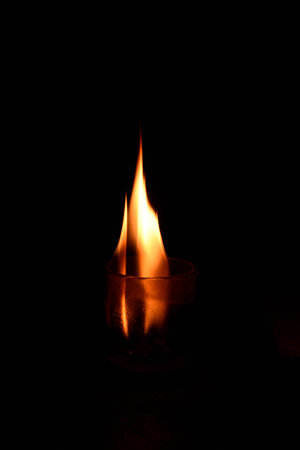 Burning candle in a glass on a black background, close-upの写真素材
