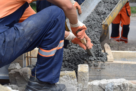Concrete is spreading in foundation over reinforcing steel bars. Concrete is flowing over...