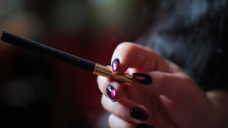 Black cigarette with golden filter in woman's handの写真素材