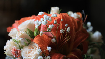 Cream roses,orange lilies and tiny white flowers,details of the wedding bouquetの写真素材