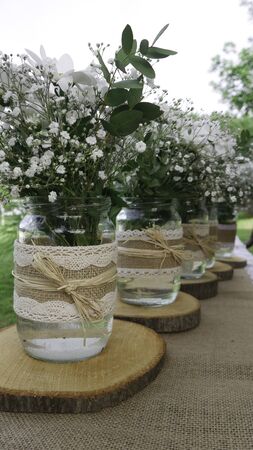 Bouquets of white daisy flowers in retro jars on wooden stumpsの写真素材