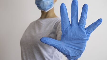 Woman with a medical mask and hands in latex glove shows the symbol STOP. Stop the disease.の写真素材