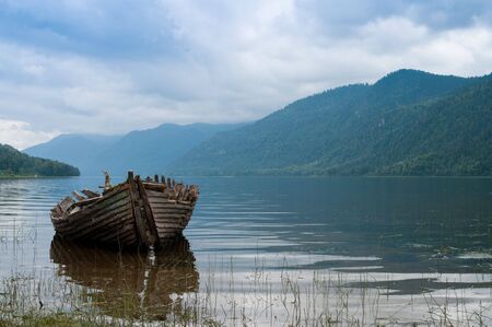 Old boat skeleton on the mountain lake in the hazy morningの写真素材
