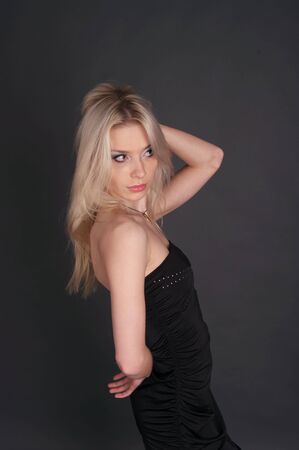Beautiful sexy blonde in the black evening gown over gray background.の写真素材