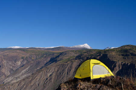 Yellow tourist tent stends on the brink of a precipiceの写真素材