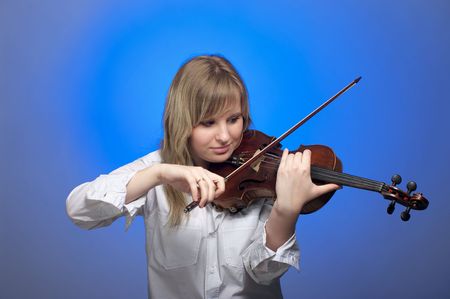 Cute female violinist playing on the violin with blue backgroundの写真素材
