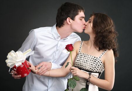 Happy young kissing couple with gift and red roseの写真素材
