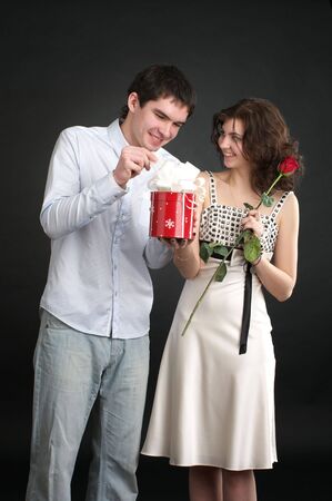 Happy young couple with gift and red rose isolated on a white background.の写真素材