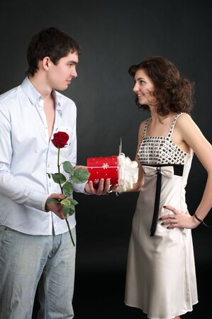Happy young couple with gift and red rose isolated on a white background.の写真素材