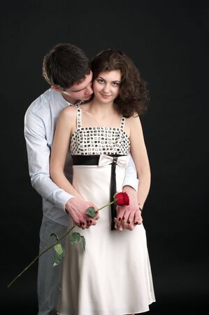 Portrait of beautiful sexual couple with red rose over blackの写真素材