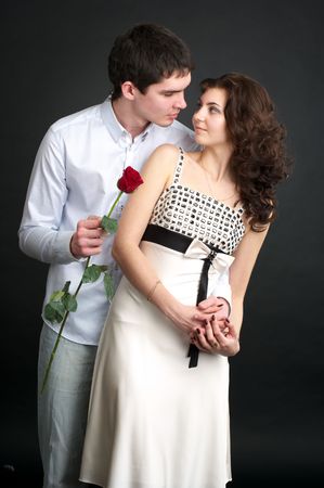 Portrait of beautiful sexual couple with red rose over blackの写真素材
