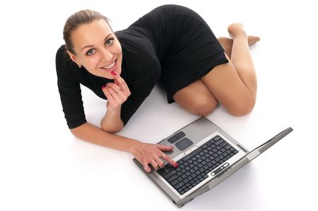 Attractive cheerful woman lying on the floor with laptop over whiteの写真素材