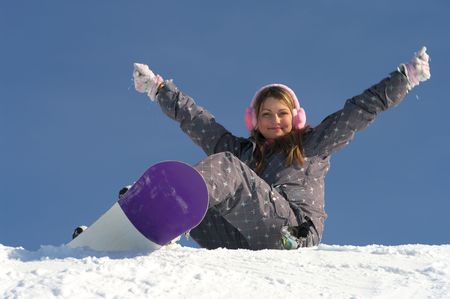 Beautiful snowboarder girl sitting on the snow and hands upの写真素材