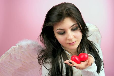 White angel girl with two red small hearts in the handの写真素材
